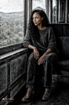 África, sentada junto a la ventanilla de un tren, contempla el paisaje gris durante el viaje hacia la costa.