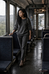 África camina por el pasillo de un antiguo vagón de tren, vestida con jersey y pantalón gris.