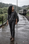 África avanza por un andén mojado junto al tren, bajo un cielo cubierto.