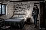 África entra vestida en una austera habitación de pensión, con cama de hierro, piedra y luz tenue.