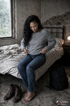 África, ya vestida con jersey gris y vaqueros, se ajusta la ropa sentada en la cama deshecha.