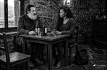 F. J. Pineda y África conversan sentados a una mesa de la taberna durante el reportaje, en blanco y negro.