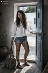 Alina regresa a Casa Salobre con camisa blanca, pantalón corto y su bolsa de viaje.