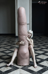 Composición surreal con una gran dedo en primer plano sobre un suelo ajedrezado, junto a una pequeña figura humana.